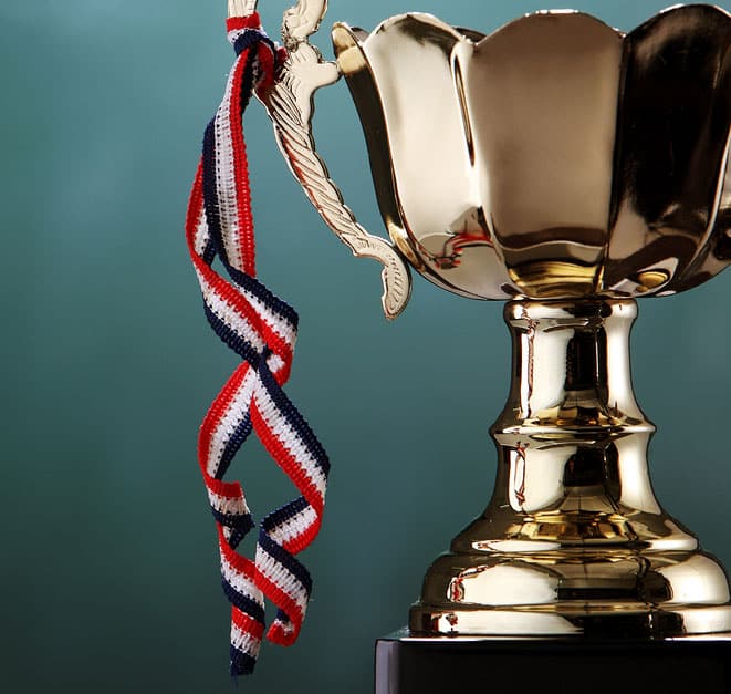 Golden trophy with draped tricolor ribbon on teal, symbolizing victory and honor.