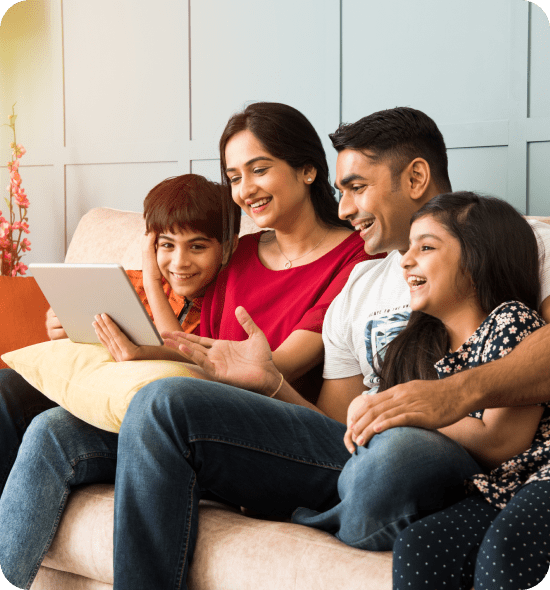 Family of four enjoys tablet time together in cozy living room.